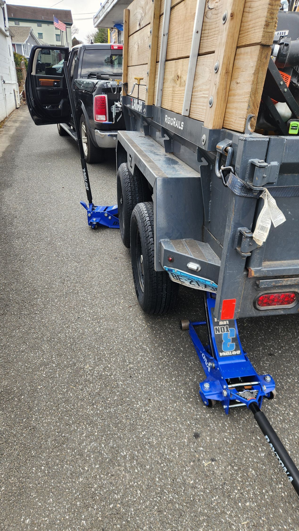 A truck is being towed by a trailer with boxes on it.
