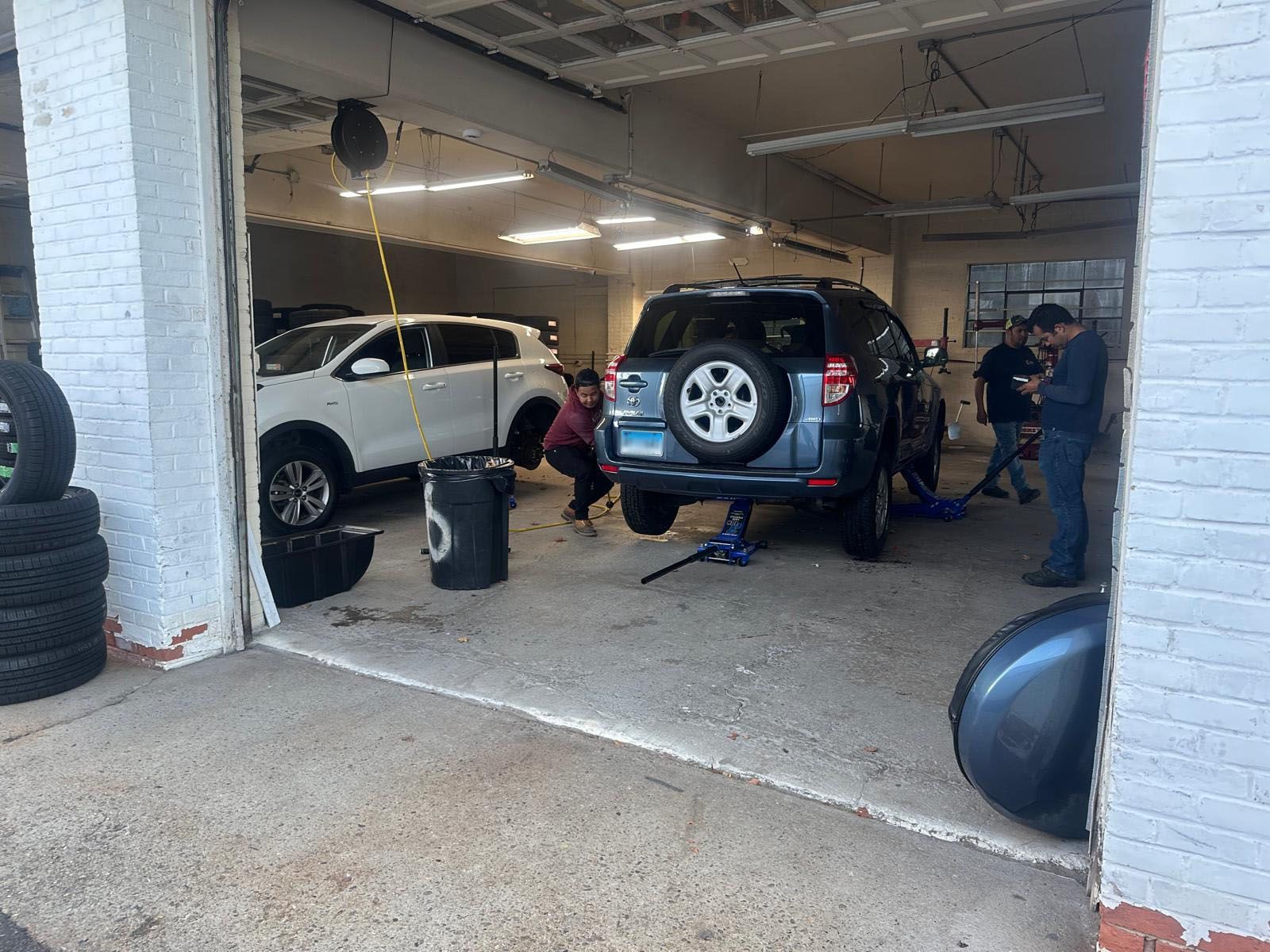 A group of people are working on a car in a garage.