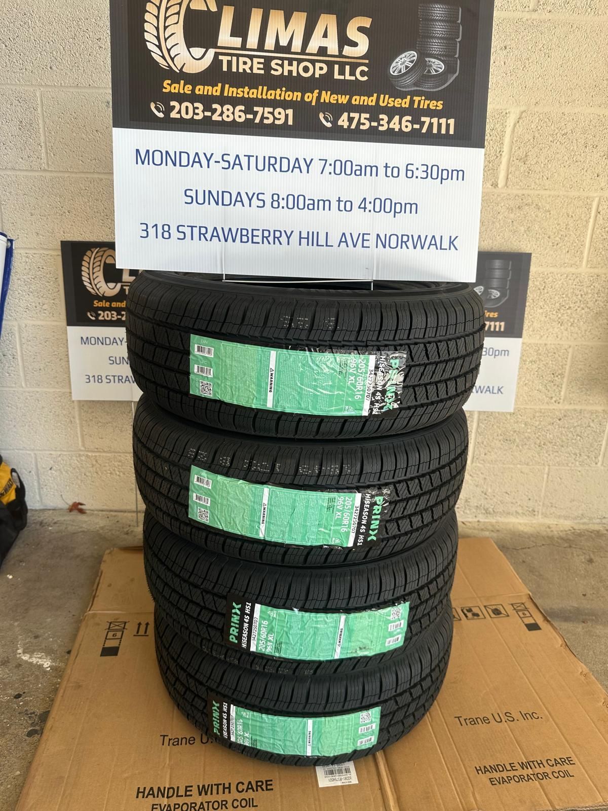 Four tires are stacked on top of each other on a cardboard box.