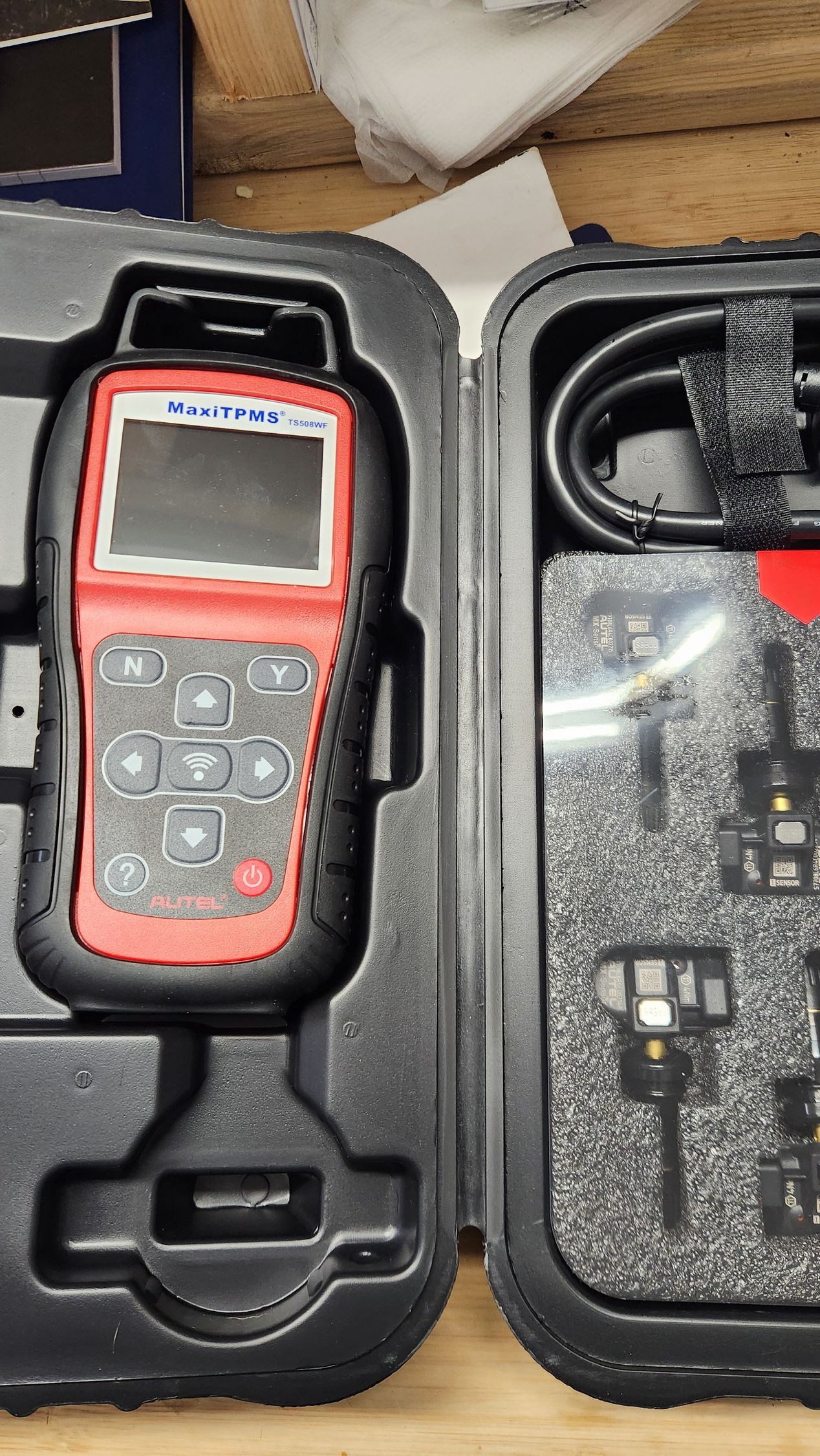 A red and black device is sitting in a case on a wooden table.