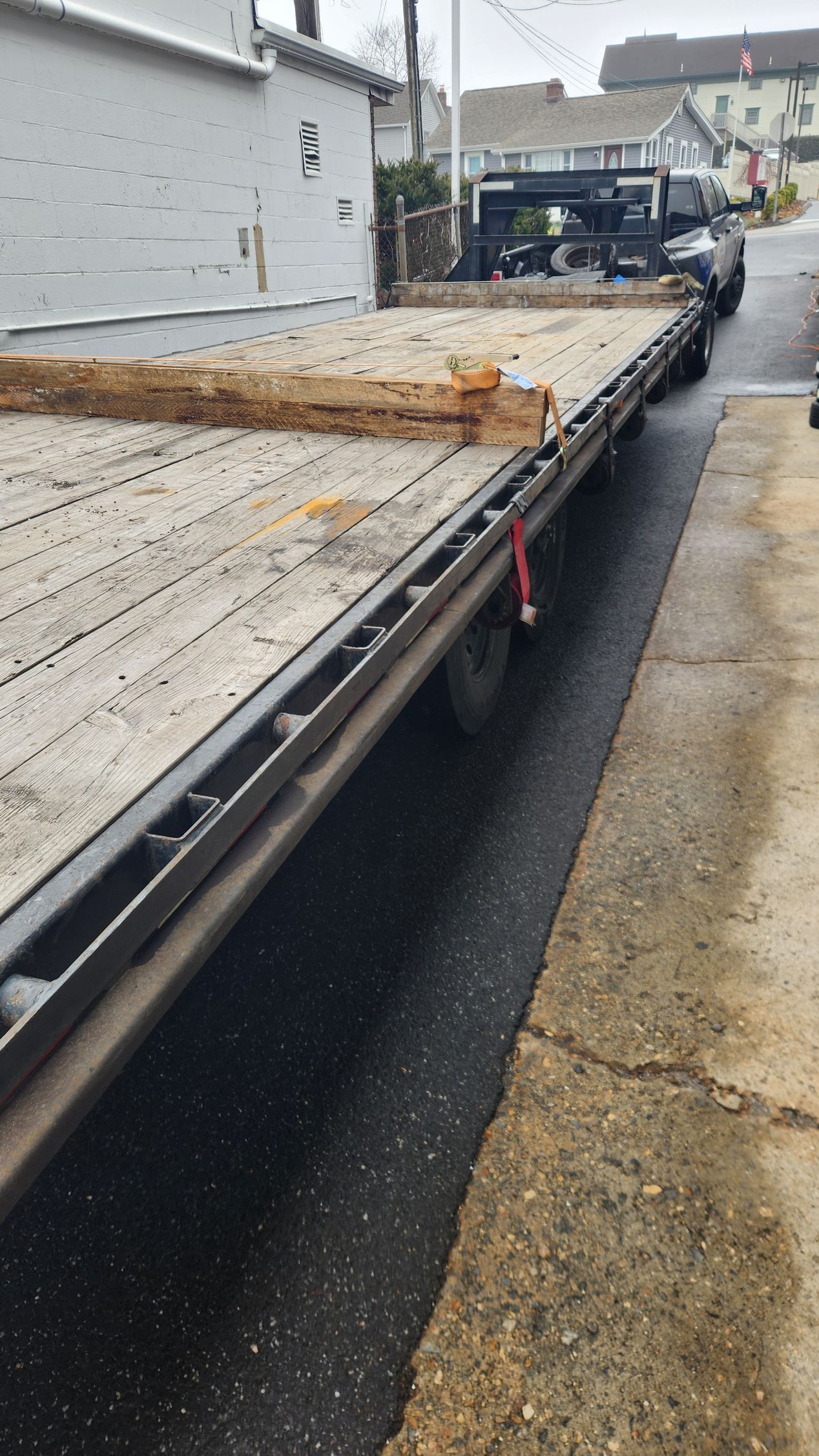 A flatbed tow truck is parked on the side of the road.
