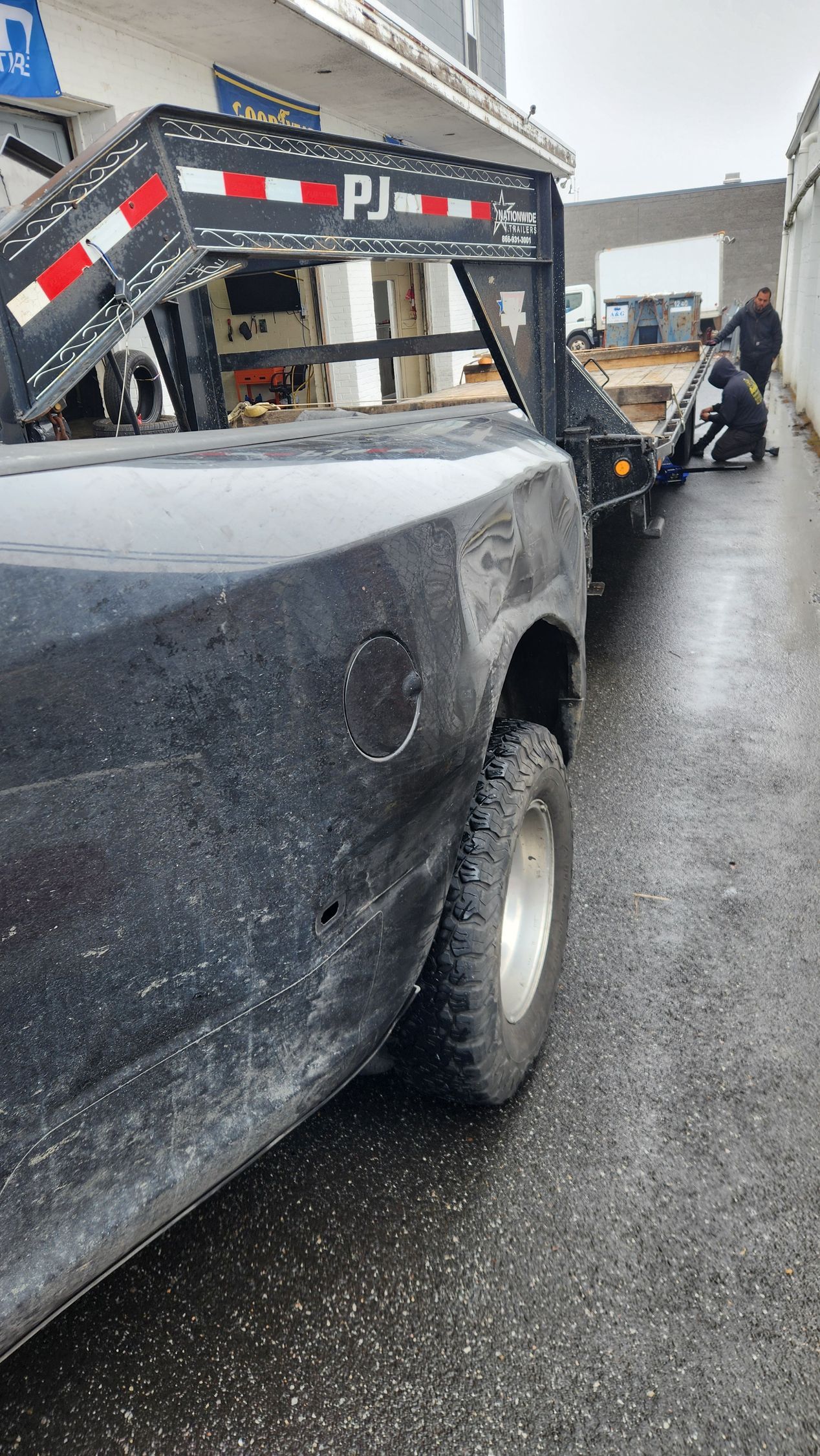 A black truck is being towed by a tow truck.