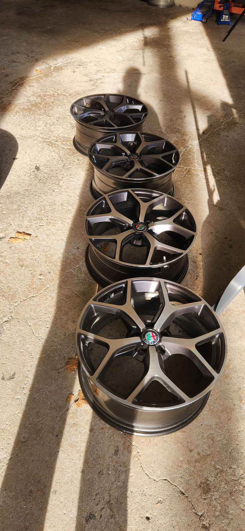 A row of black wheels are sitting on a concrete surface.