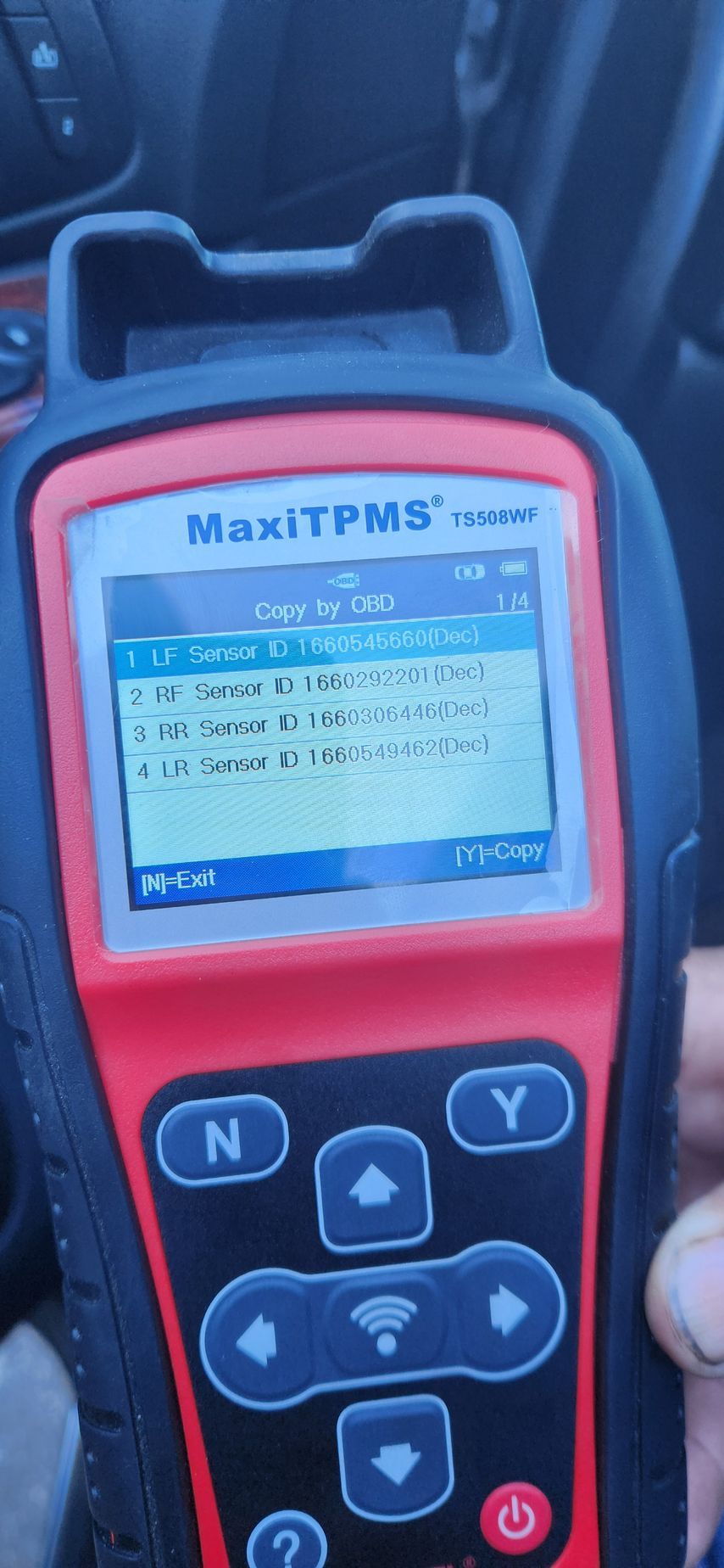 A person is holding a red and black device in their hand.