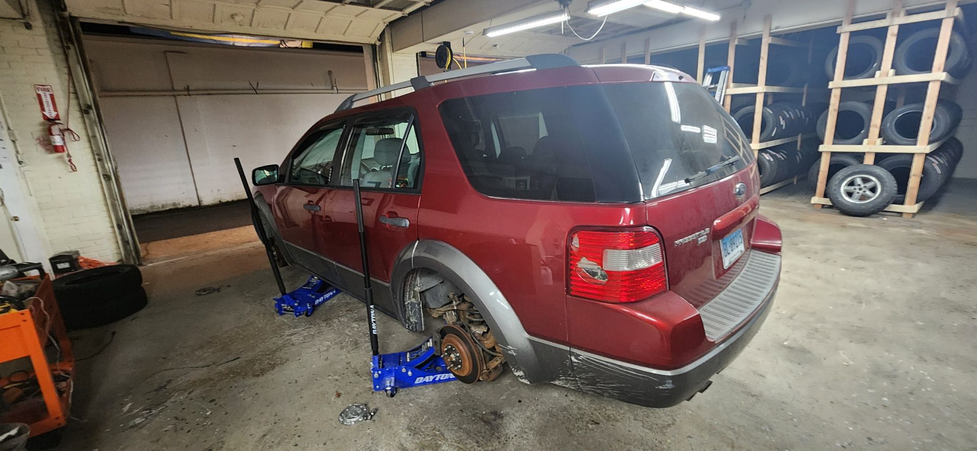 A red suv is sitting on a jack in a garage.
