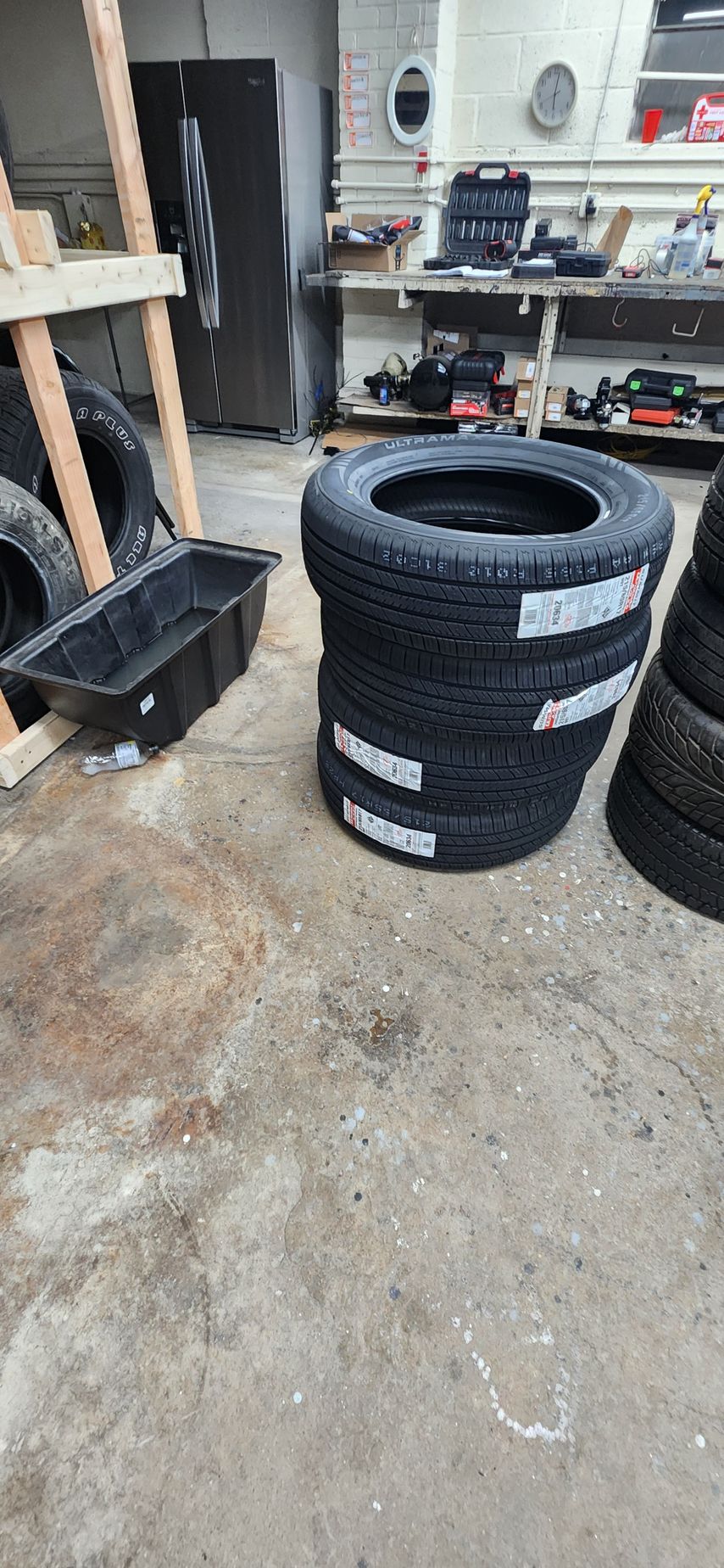 A bunch of tires are stacked on top of each other in a garage.