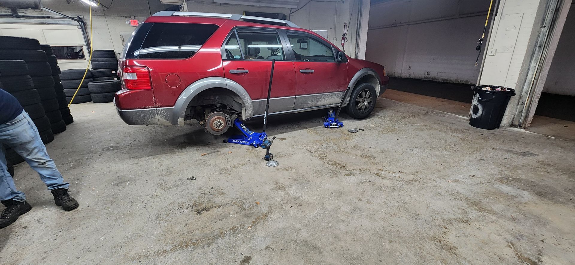 A red suv is sitting on a jack in a garage.