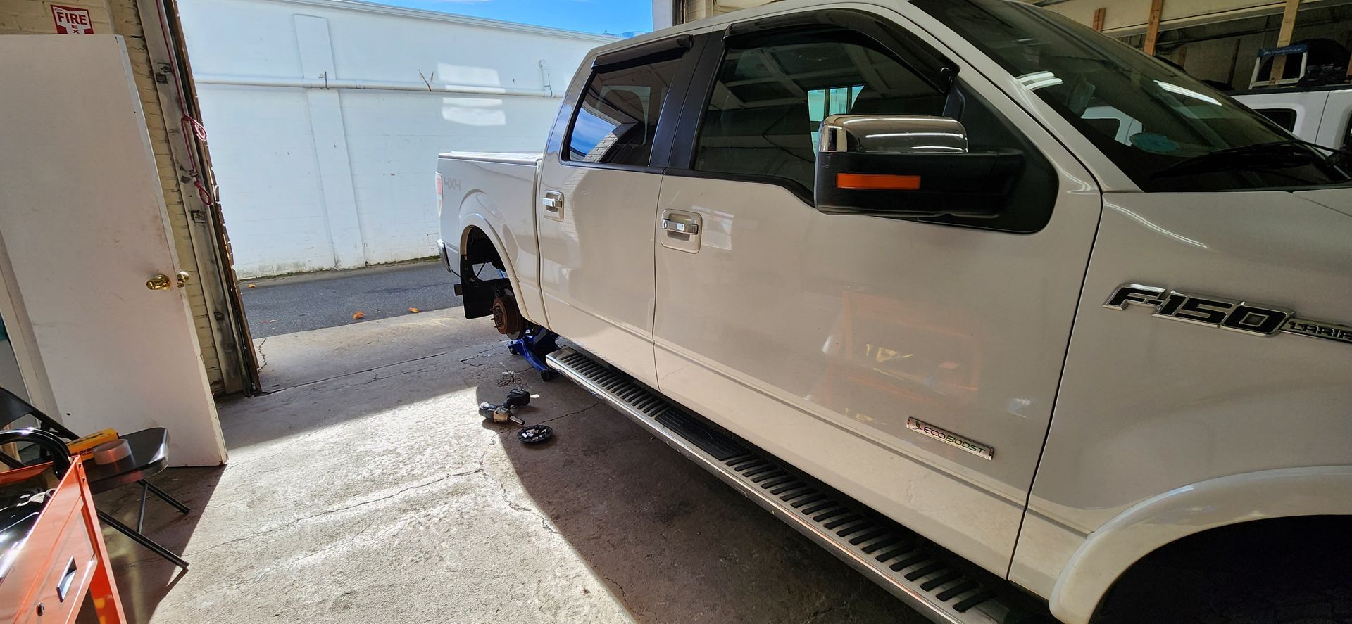 A white truck is parked in a garage next to a door.