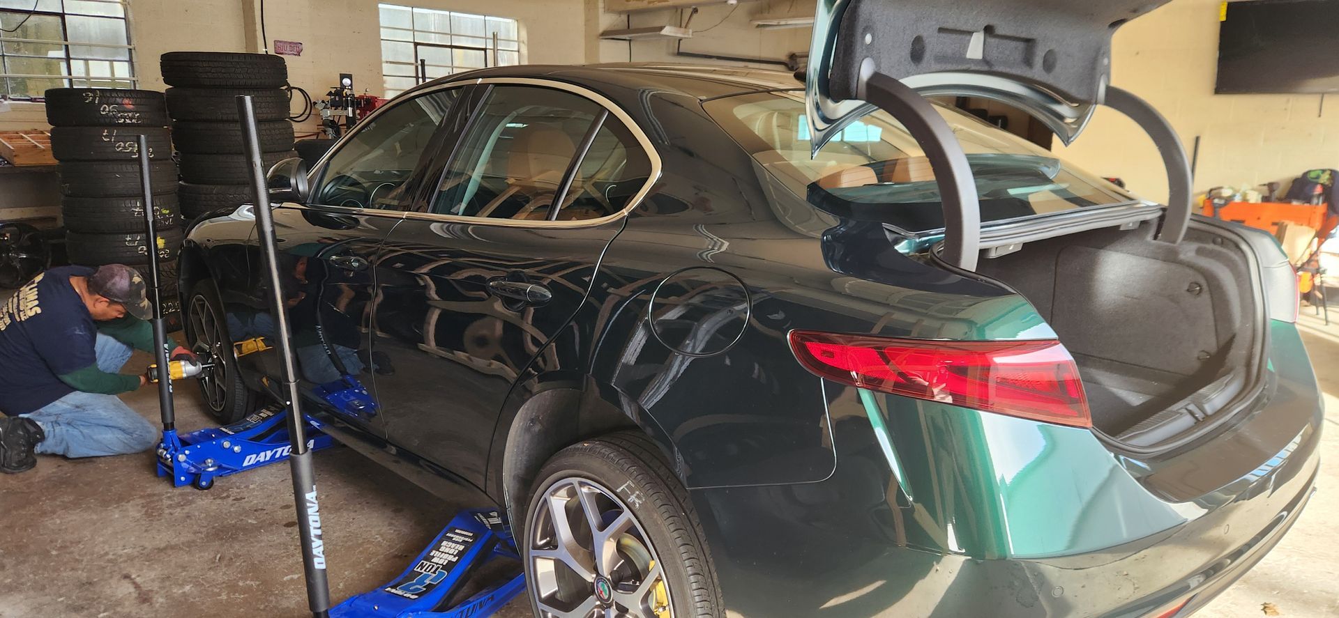 A man is working on a black car in a garage.
