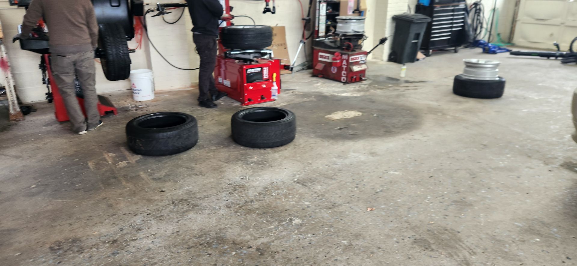 A man is changing a tire in a garage.