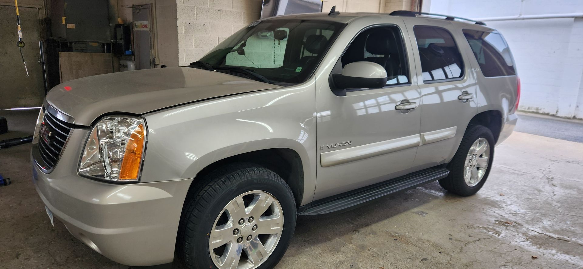 A silver gmc yukon is parked in a garage.