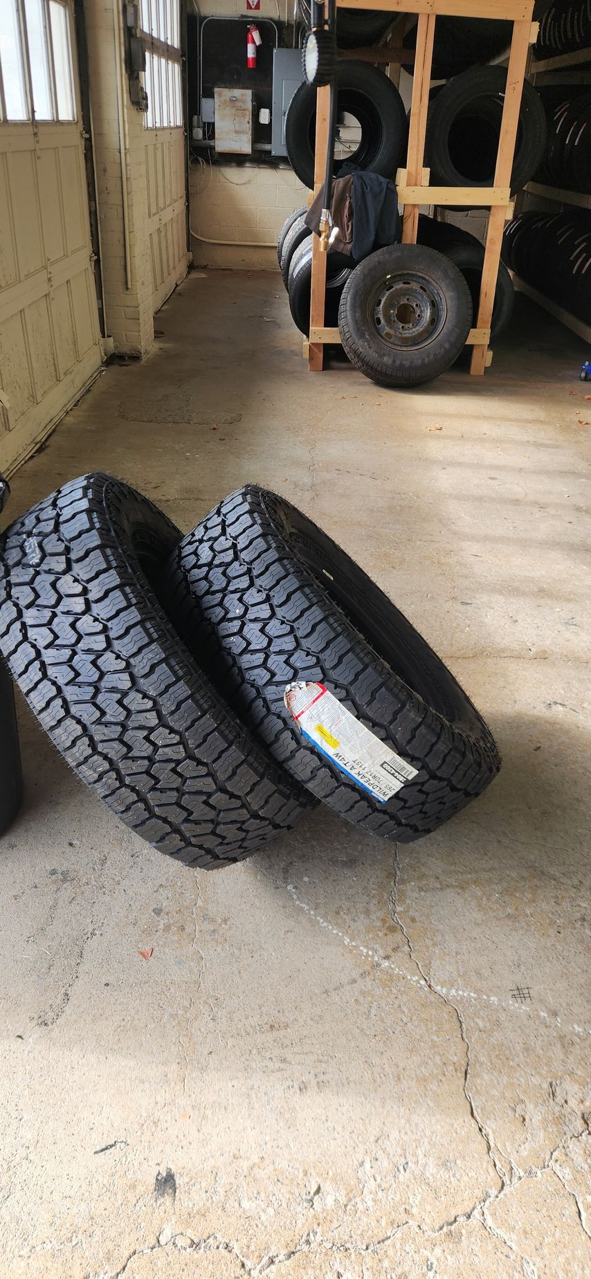 Two tires are stacked on top of each other in a garage.