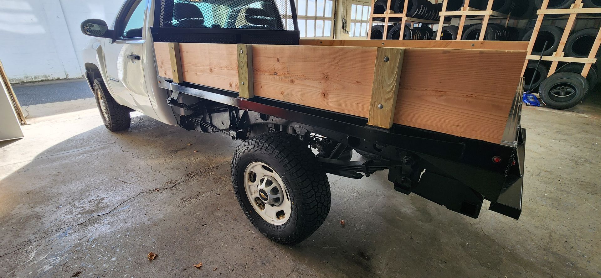 A truck with a wooden bed is parked in a garage.