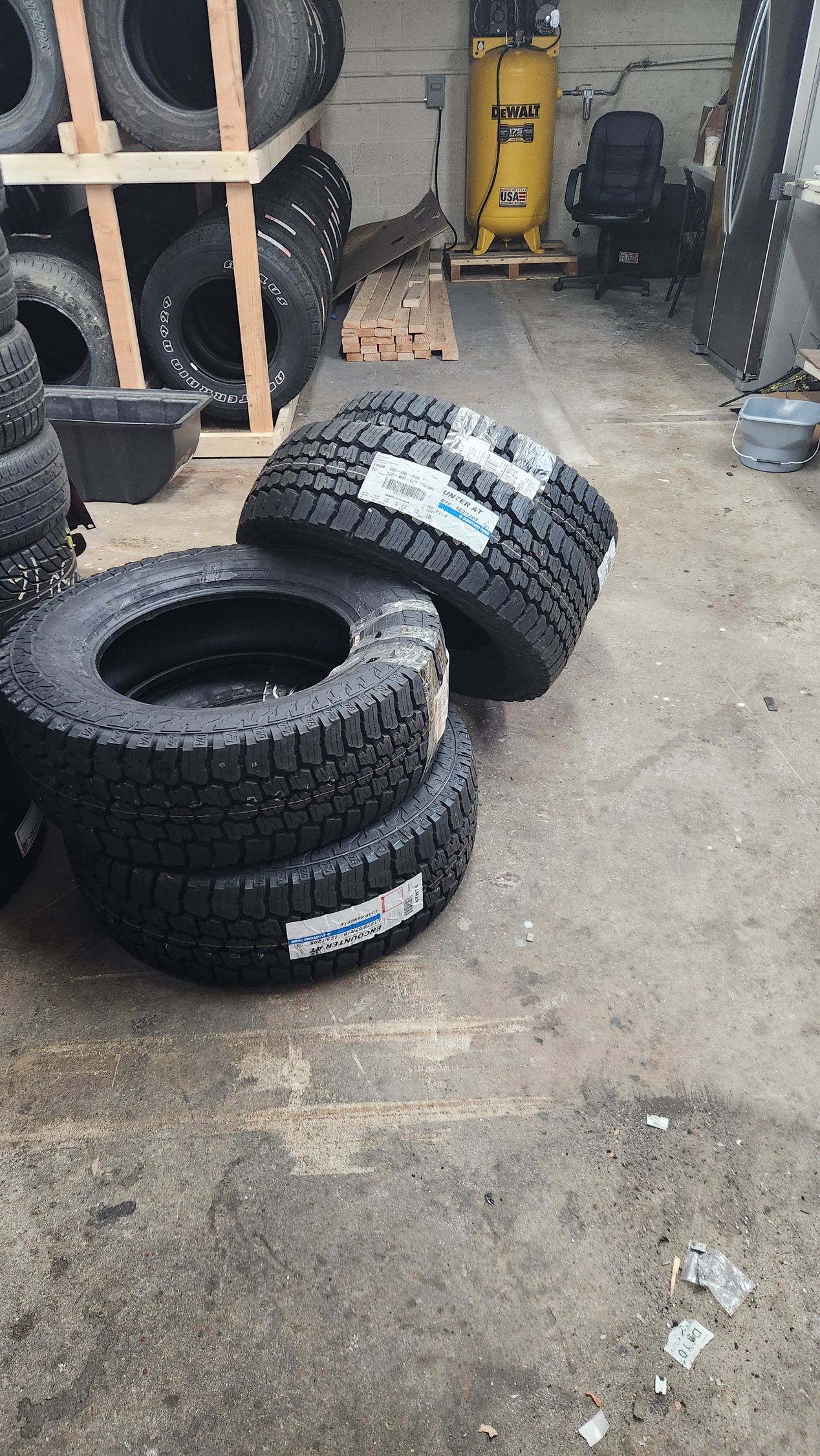 A bunch of tires are stacked on top of each other in a garage.