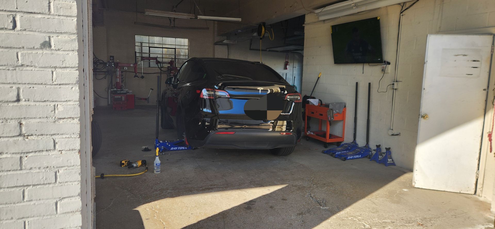 A car is parked in a garage next to a brick wall.