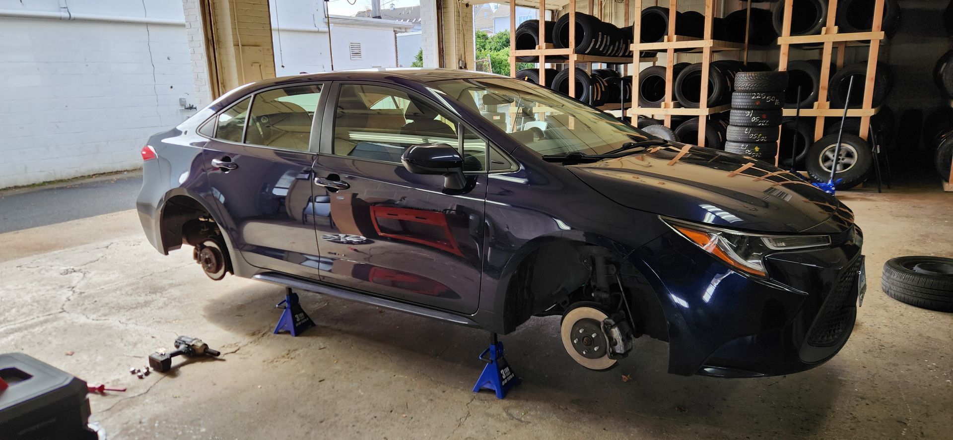 A car is sitting on jack stands in a garage.