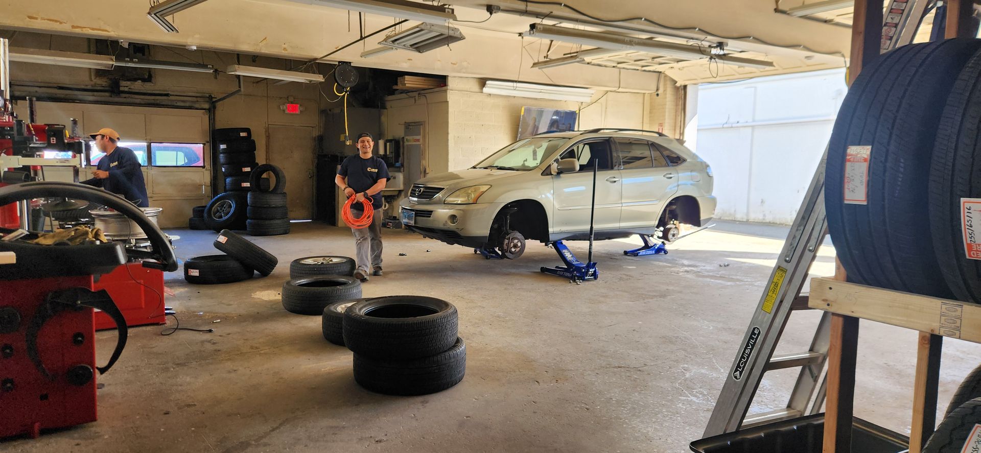A man is standing next to a car in a garage.