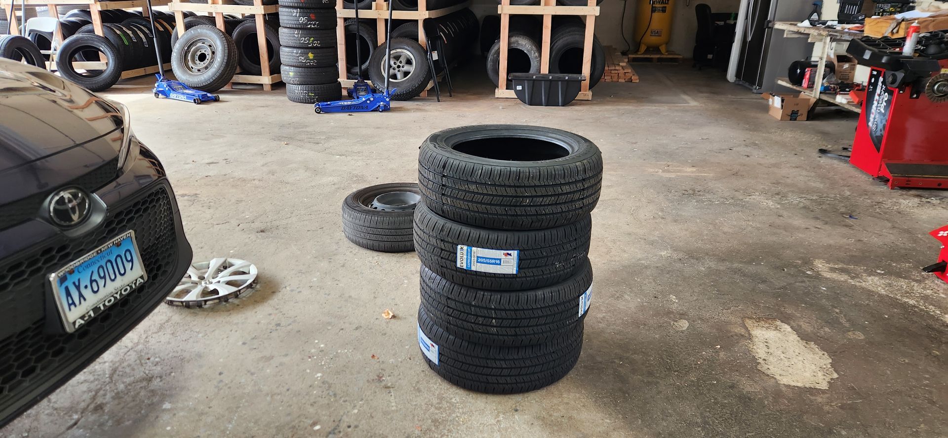 A bunch of tires are stacked on top of each other in a garage.
