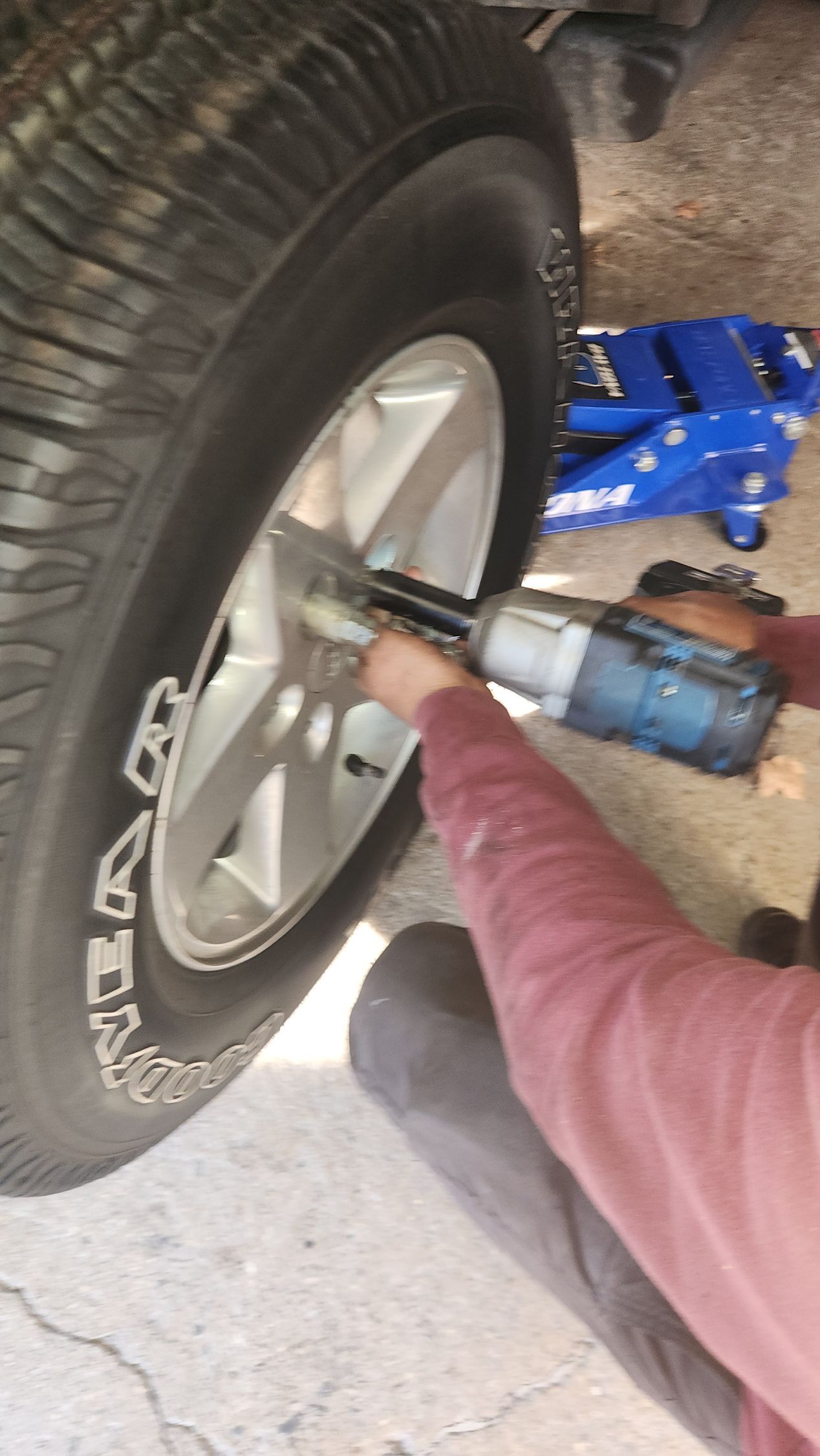 A man is changing a tire on a truck with a wrench.