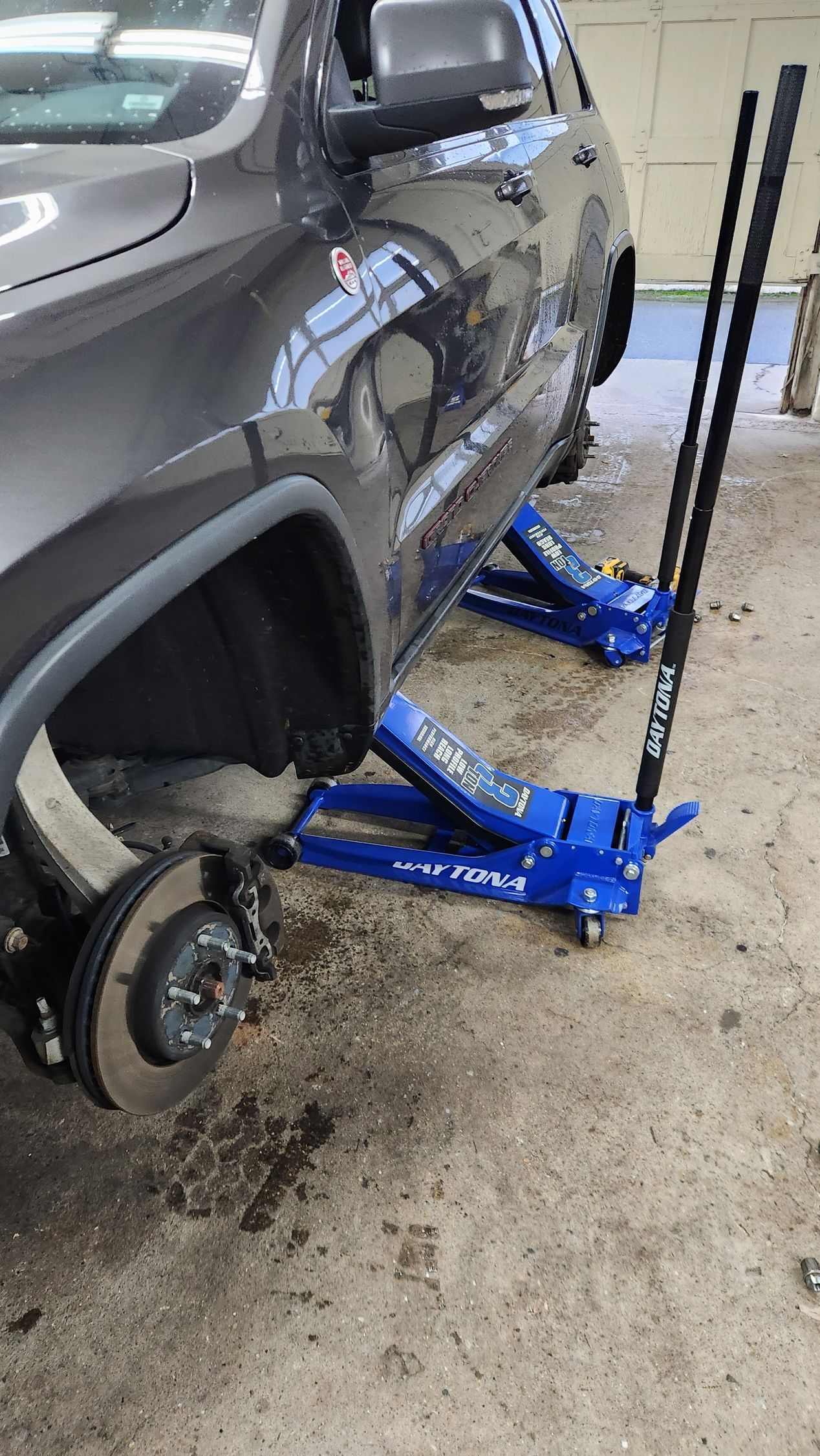 A car is sitting on a blue jack in a garage.