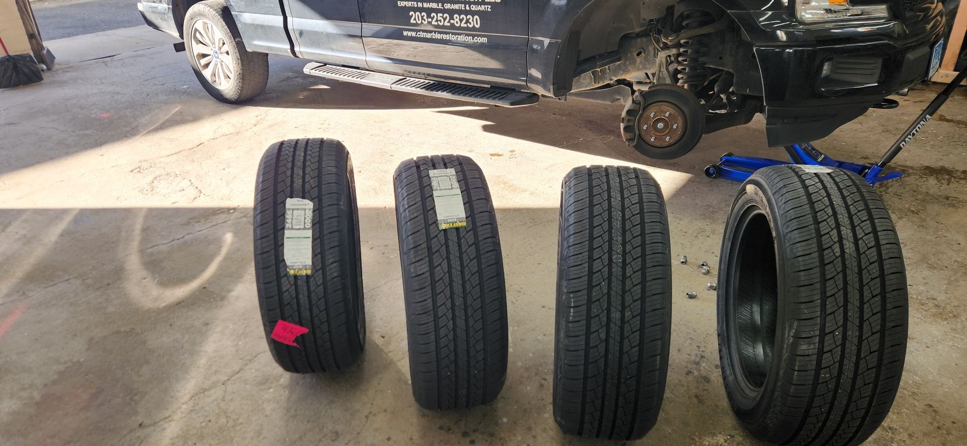 Four tires are lined up next to each other in front of a truck.