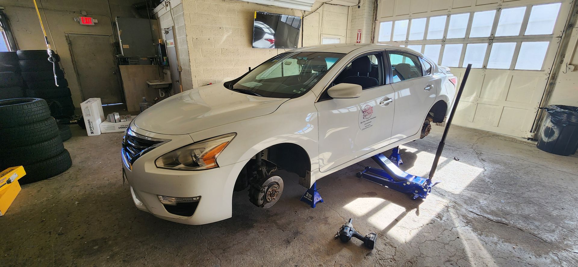 A white car is sitting on a jack in a garage.