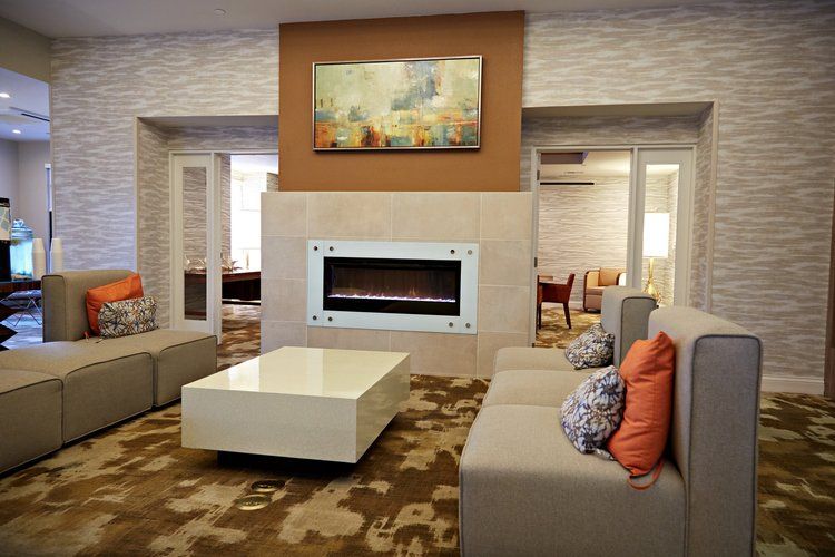 A living room with a fireplace , couch , coffee table and chairs.