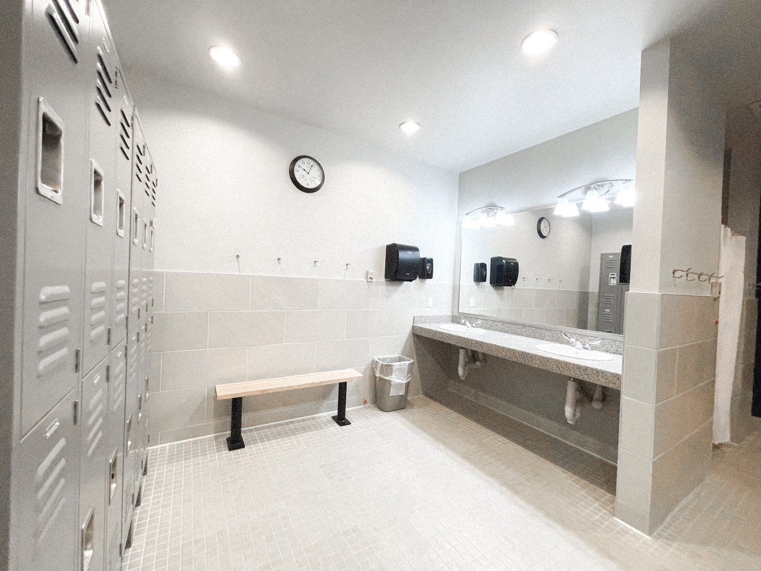 A locker room with a bench and a clock on the wall.