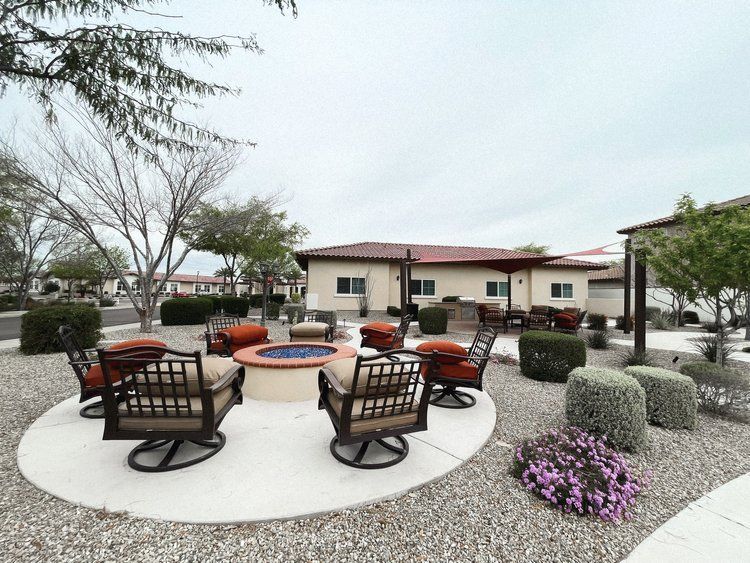 There is a fire pit in the middle of the yard with chairs around it.