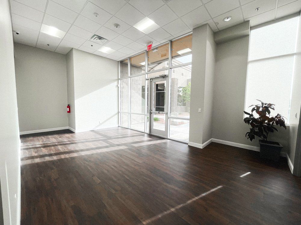 An empty room with hardwood floors and a plant in a pot.