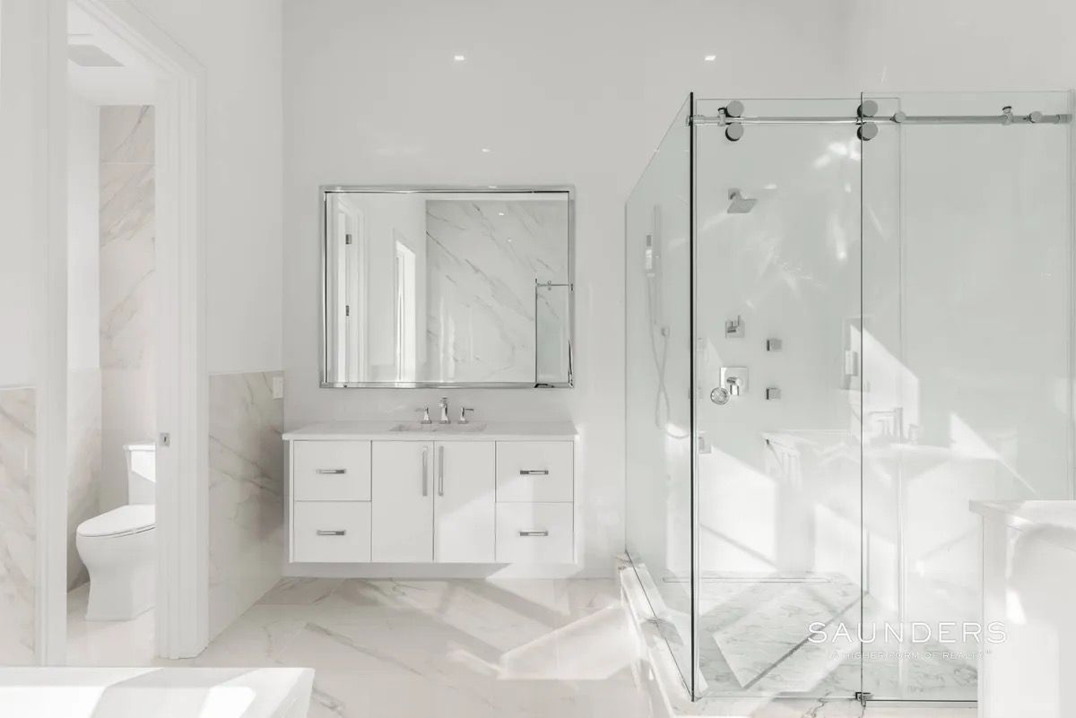 Bright white bathroom with vanity, mirror, and glass shower enclosure