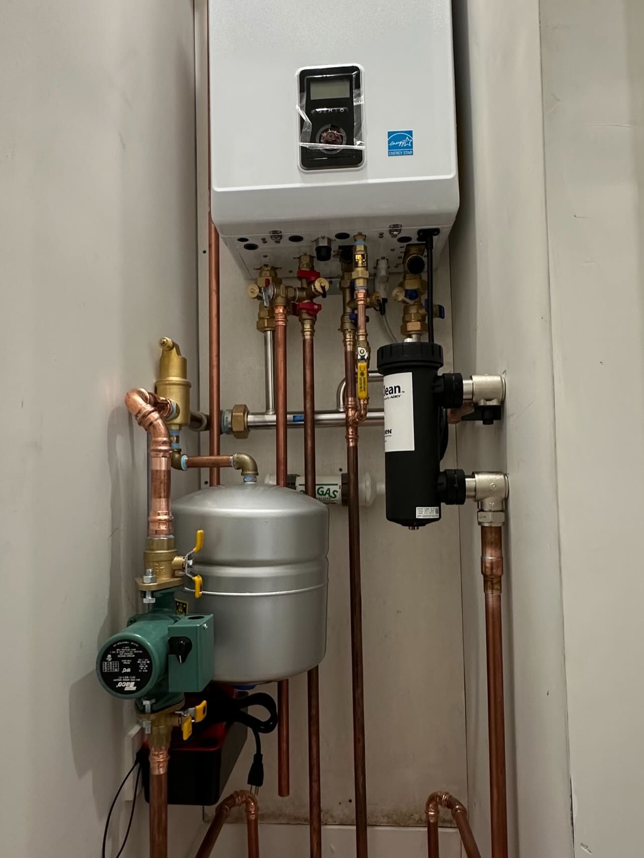 Wall-mounted boiler and exposed copper pipes in a narrow utility closet