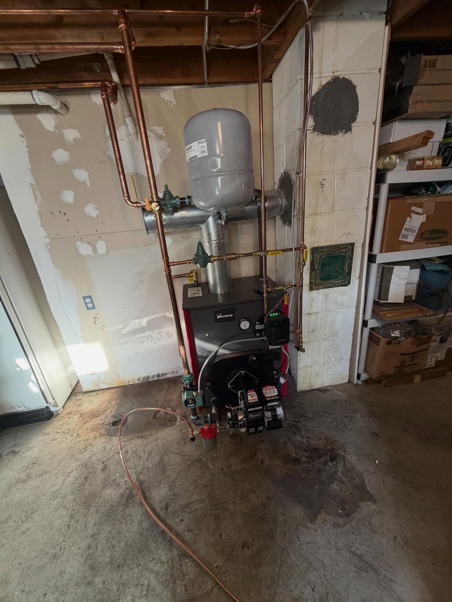 Utility pump and tank setup in a garage, with exposed pipes and drywall repairs.