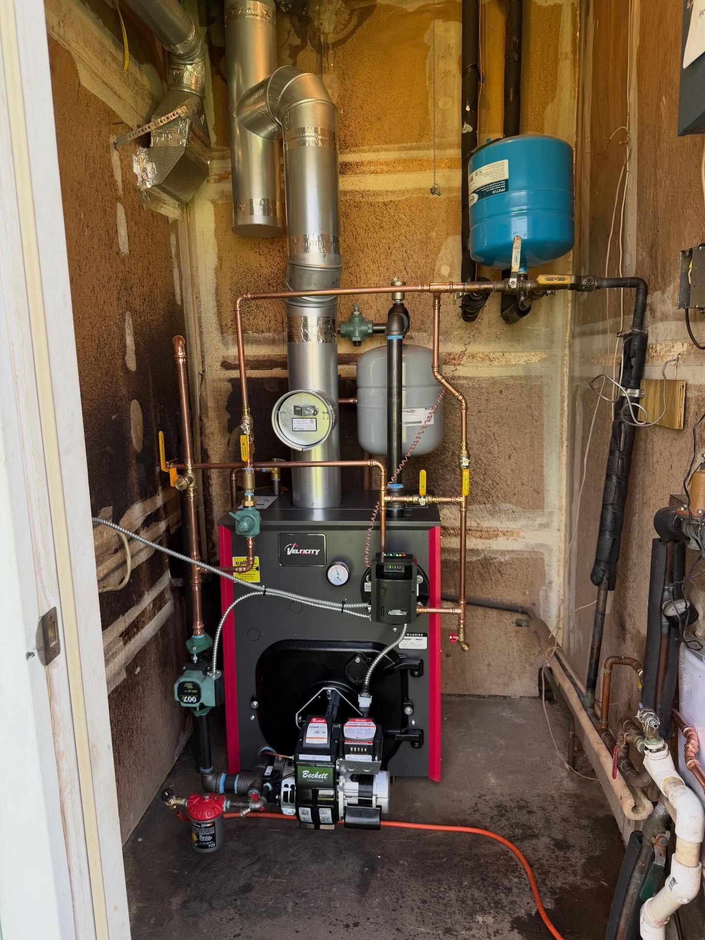 Heating boiler and piping system in a narrow utility closet with insulated walls.