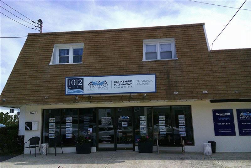 A two-story building with a brown roof, a business sign, and large glass windows.