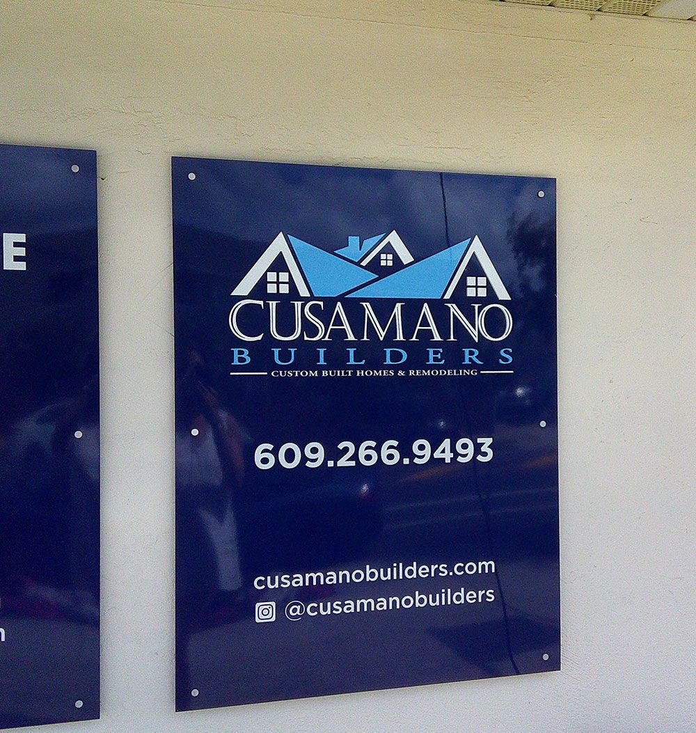 Cusumano Builders sign with logo, phone number, and website on a blue background.