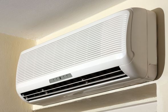 White wall-mounted air conditioner on a cream-colored wall, angled view.