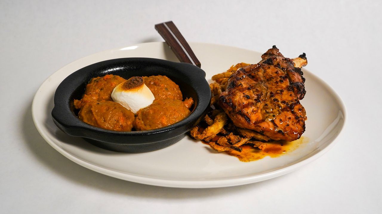 Plate of food: chicken and curry with egg and brown sauce.