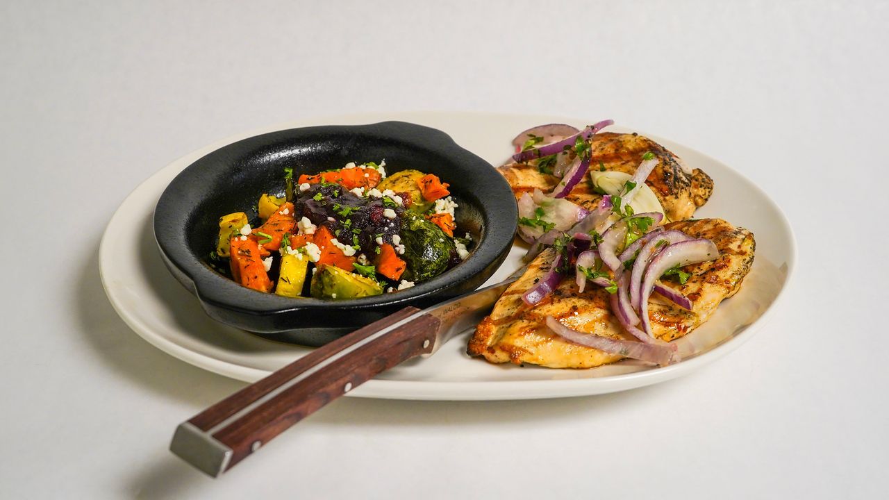 Grilled chicken and vegetable medley with red onion garnish.