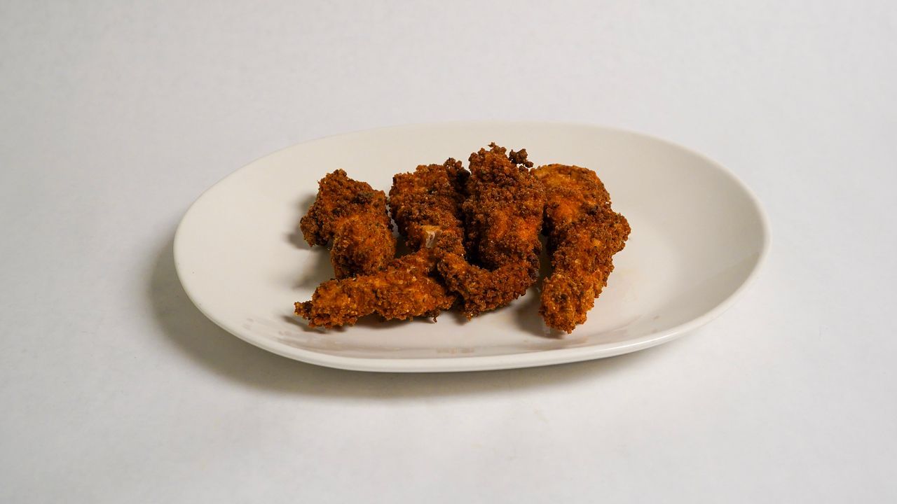Plate of fried chicken tenders on a white plate, against a white background.