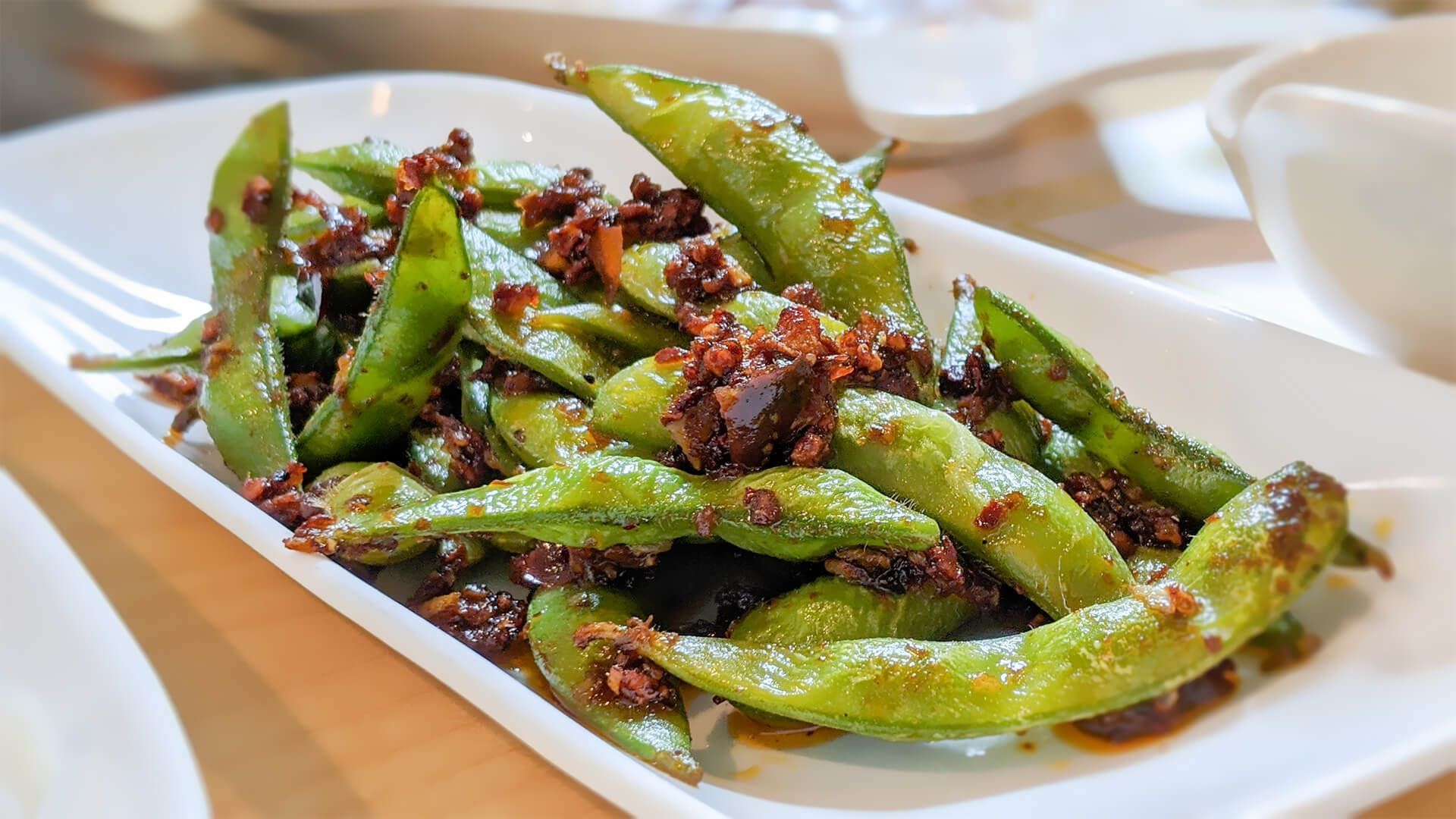 a white plate topped with green beans and meat on a table
