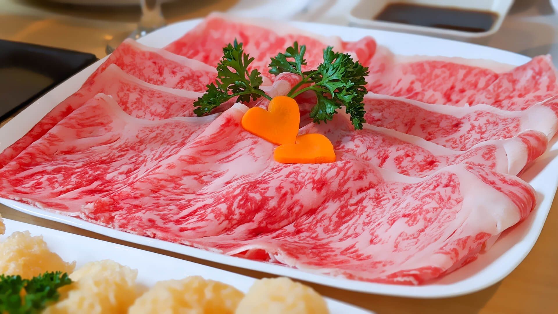 a white plate topped with slices of meat and a carrot