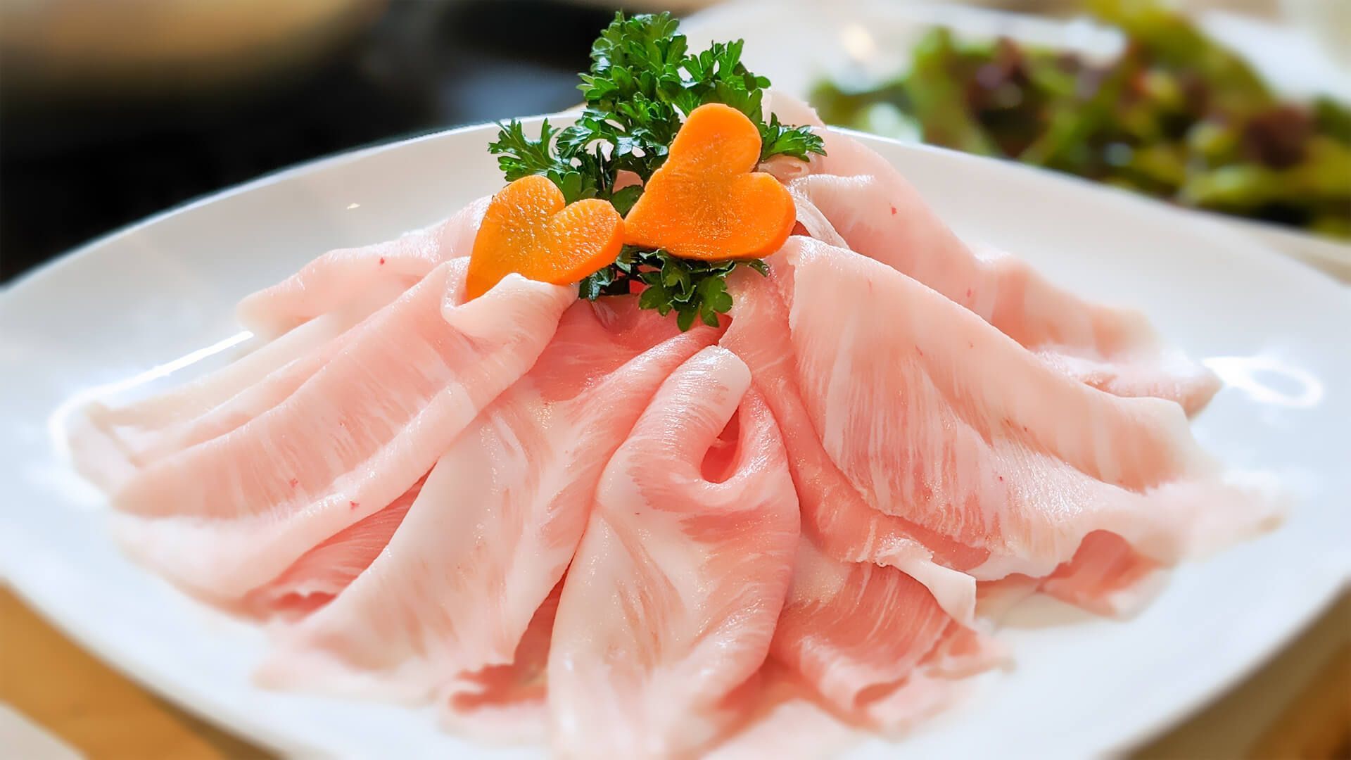 a white plate topped with sliced pork and carrots