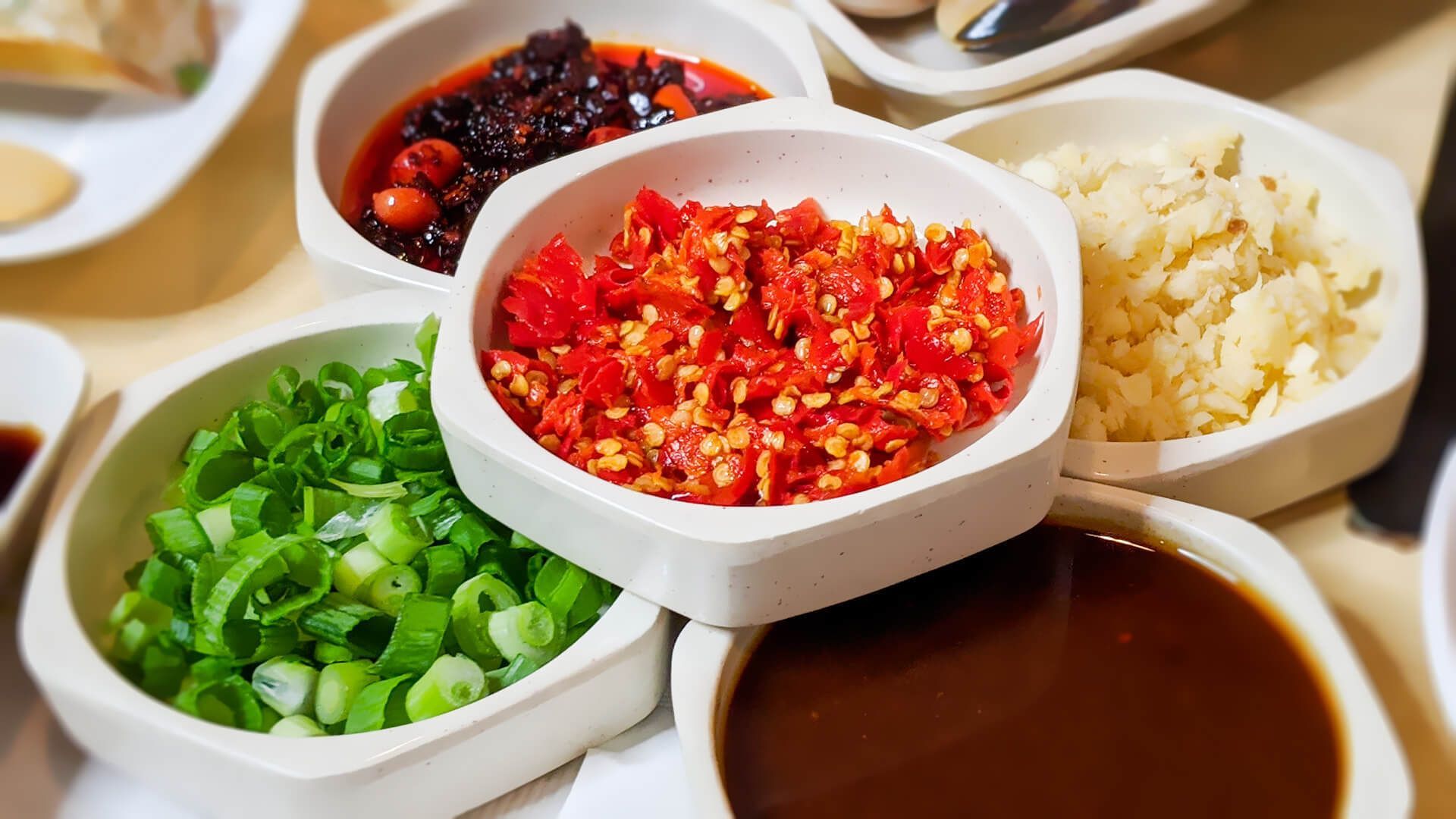 a table topped with bowls of sauces and vegetables