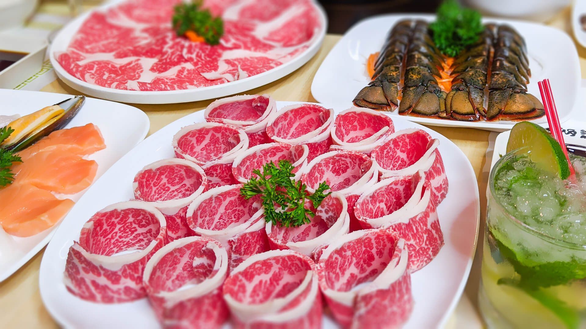 a table topped with plates of meat and a drink