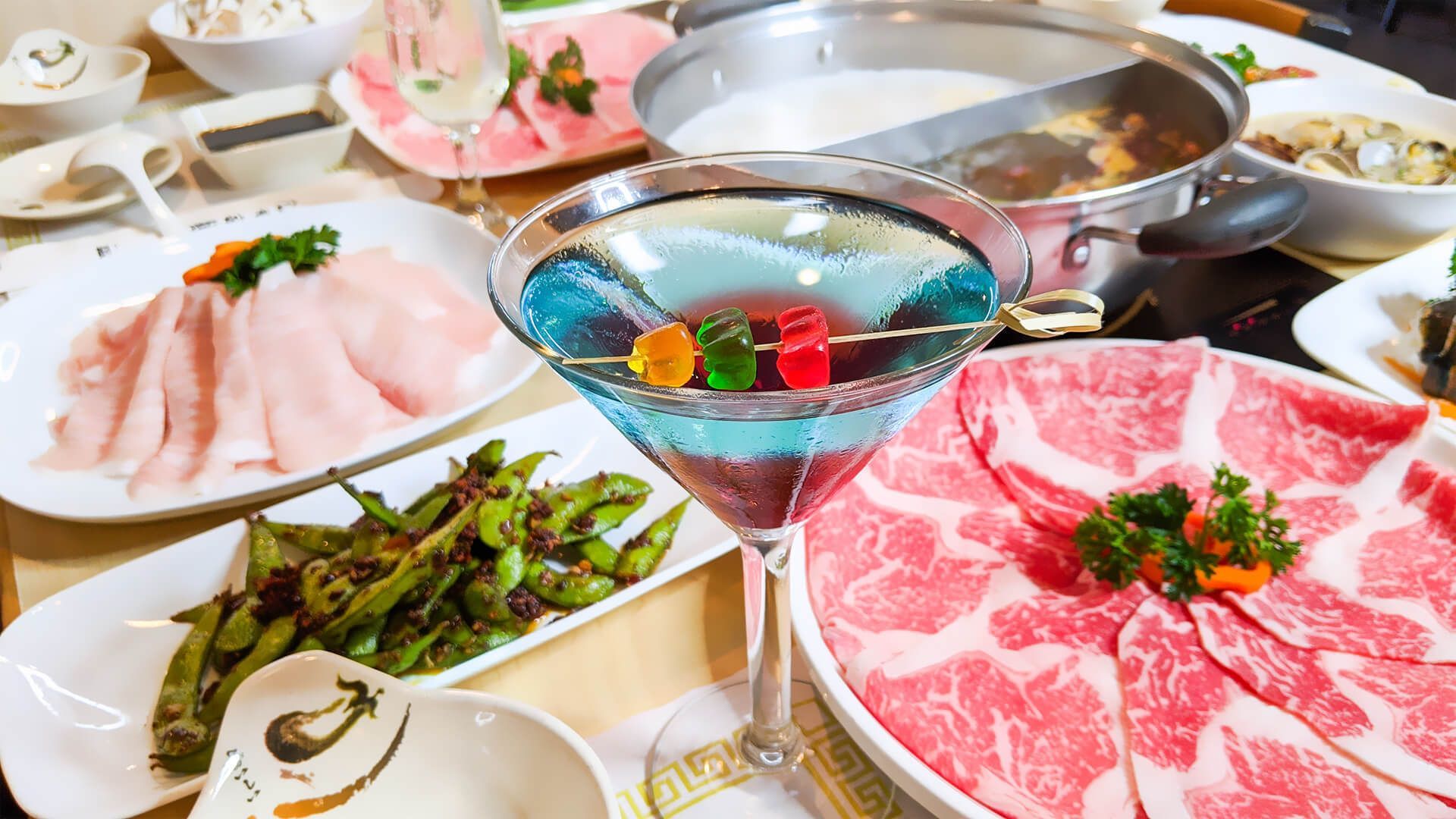 a table topped with plates of food and a martini glass filled with gummy bears
