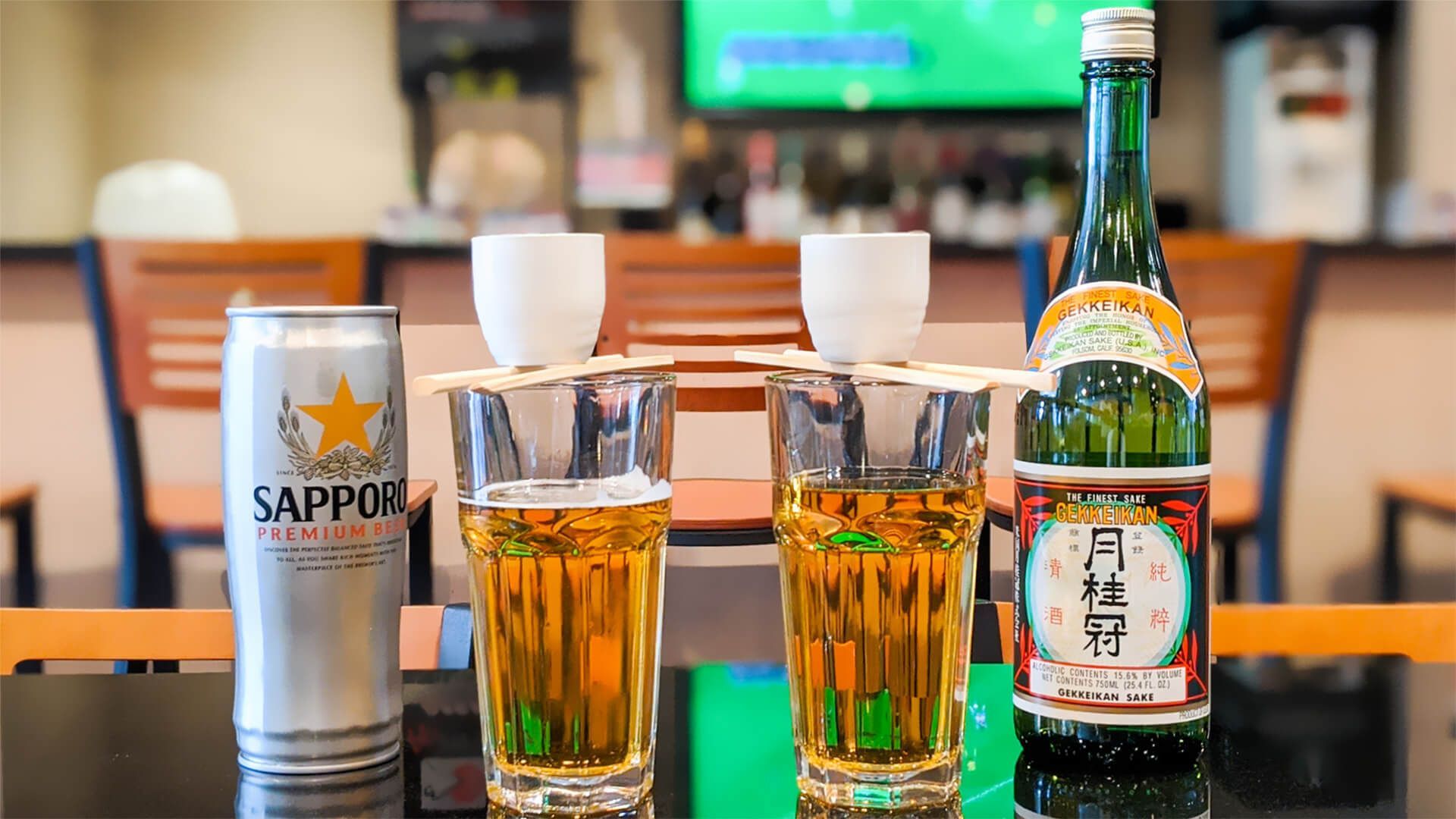 a bottle of alcohol and two glasses of beer are on a table