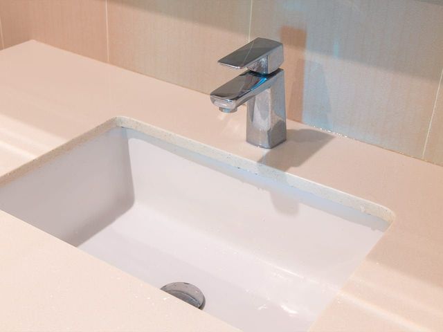 White bathroom sink with chrome faucet on a light countertop