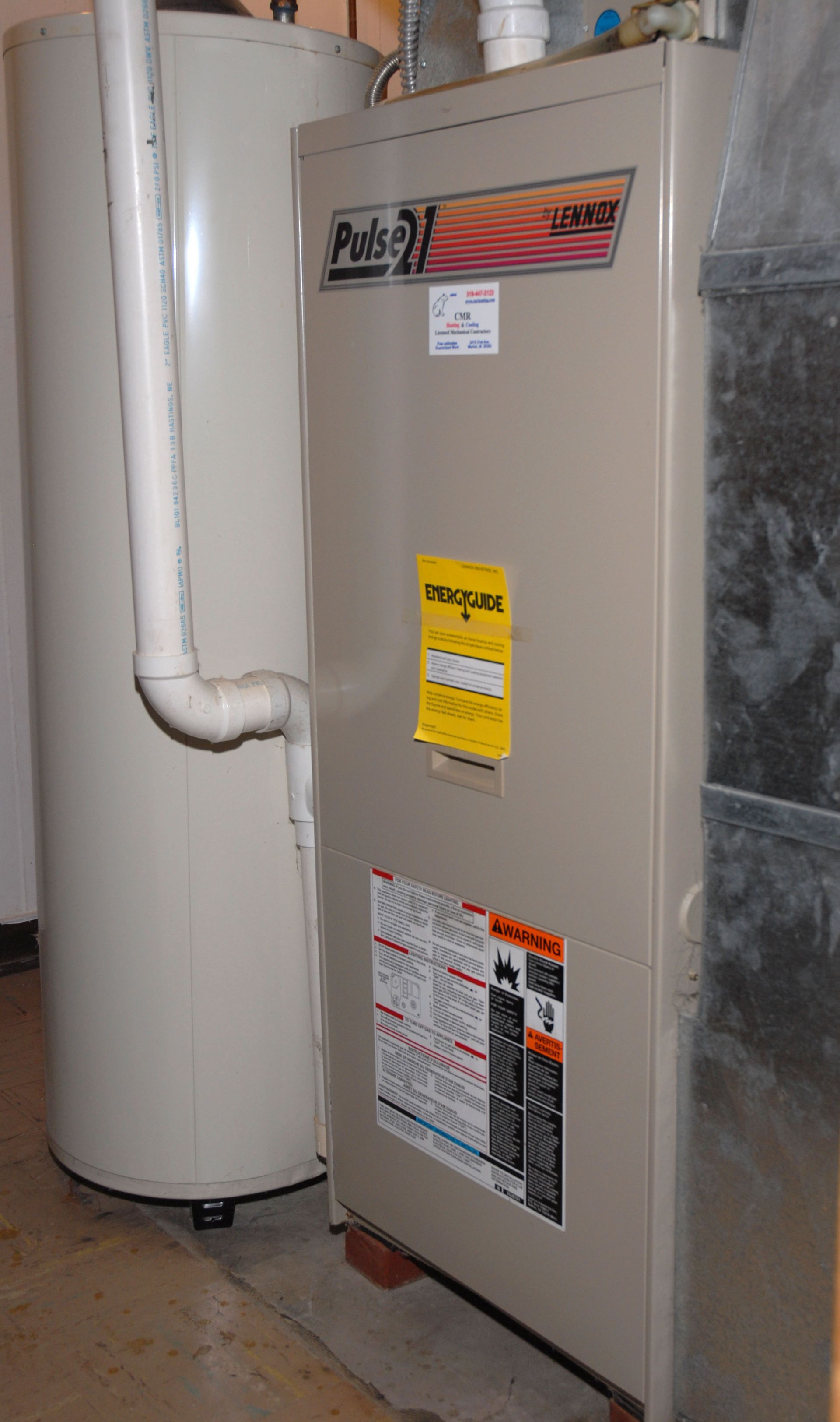Beige furnace beside a white water heater in a basement utility room.