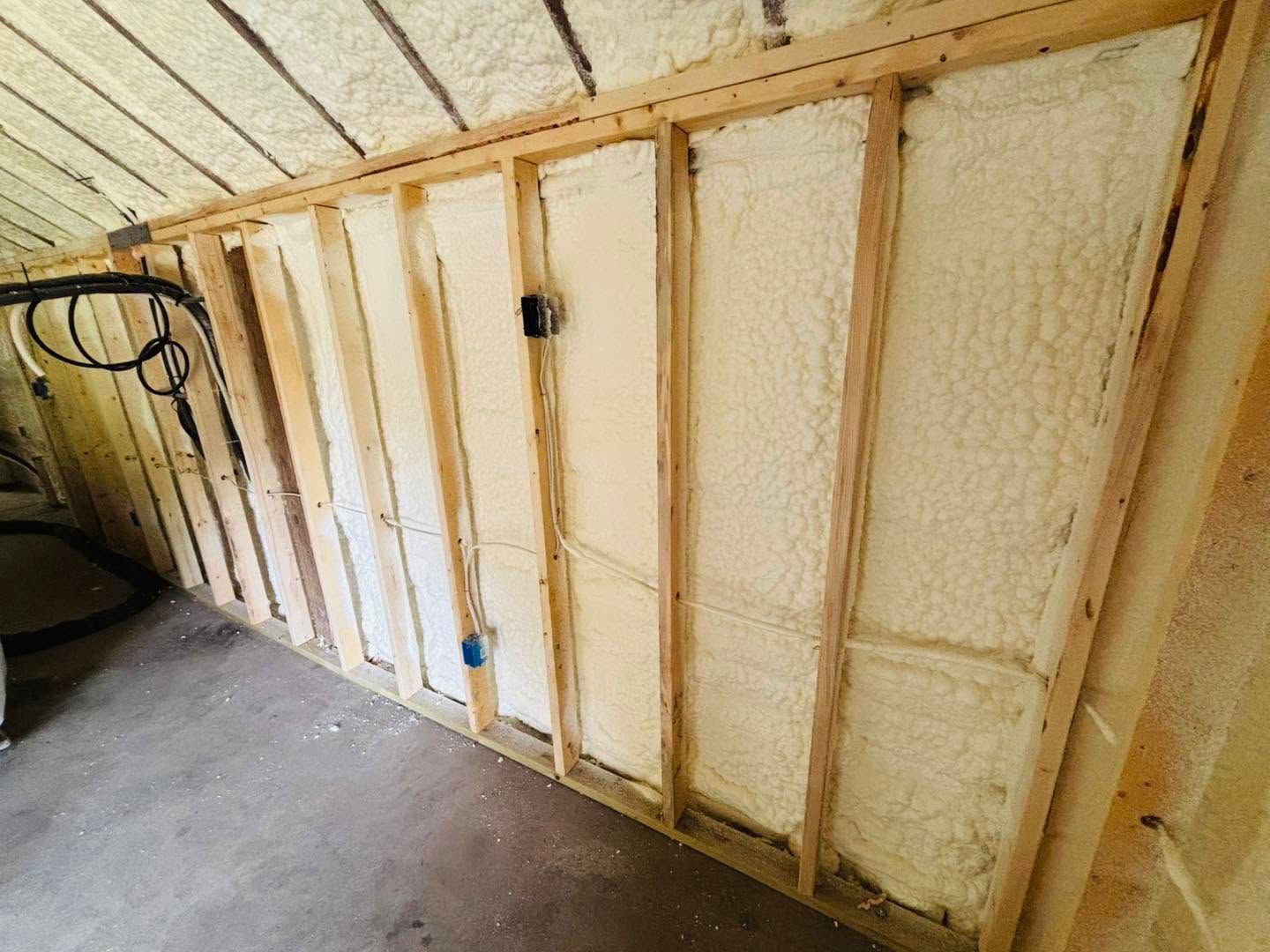Insulated wall framing in an unfinished room with exposed studs and spray foam insulation
